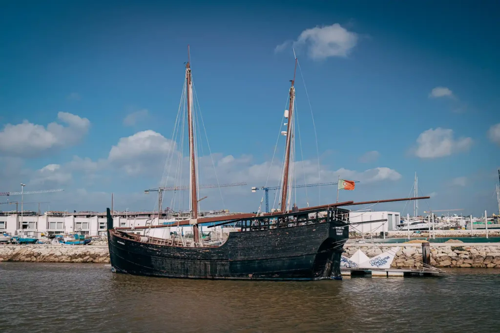Caravelle portugaise dans le port de Lagos sous un ciel bleu, ambiance maritime historique.