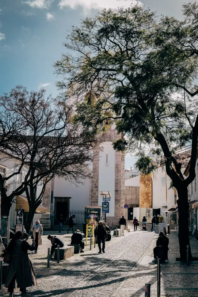 Rue animée de Lagos avec l'église de Santo António en arrière-plan, ambiance ensoleillée et paisible.