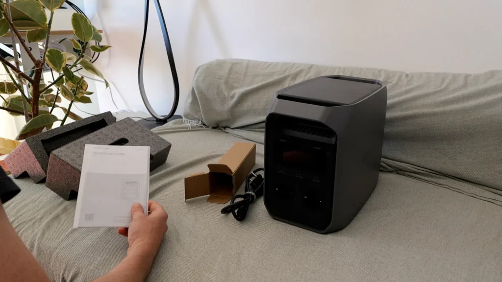 Test du générateur EcoFlow Delta 3 Classic sur un canapé, manuel en main.