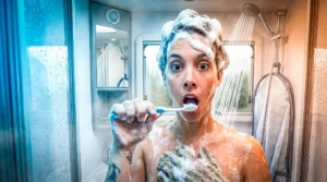 Caroline brushes her teeth in the shower of a converted van, illustrating vanlife living.