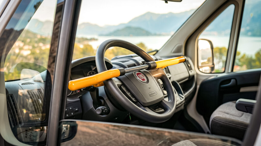 Steering lock installed in a converted van with a view of a lake and mountains in the background.