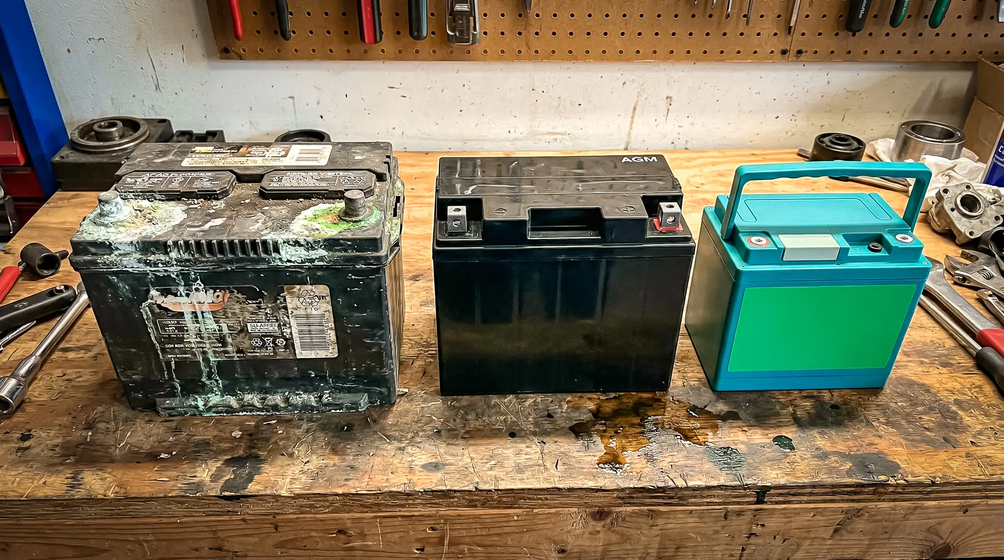 Three types of camper batteries on a wooden workbench in a workshop.