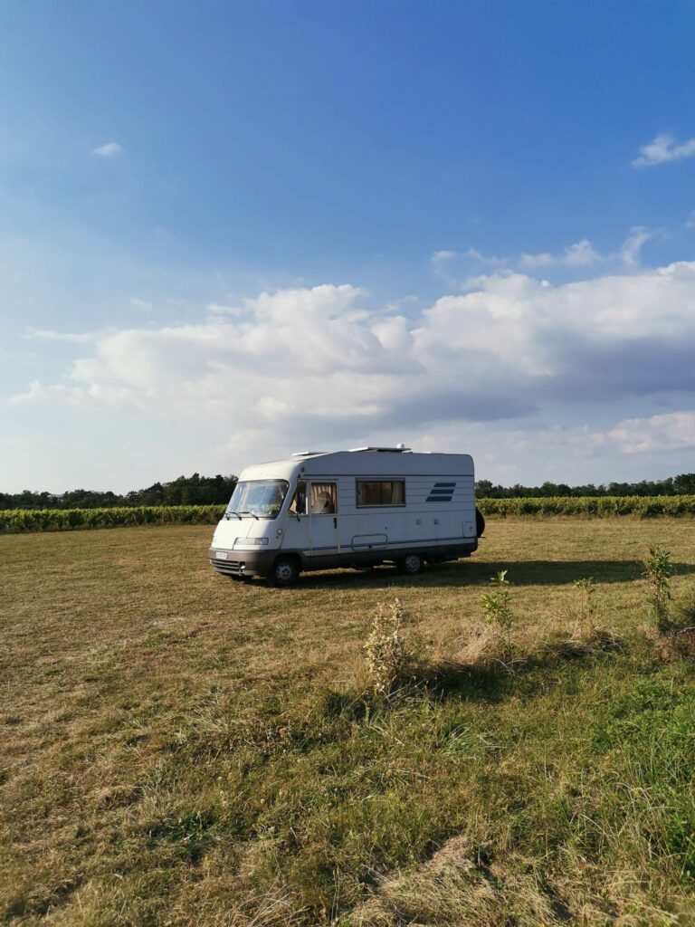 Camper van Edouard is parked in the heart of a meadow under a summer sky, illustrating the vanlife freedom in nature.