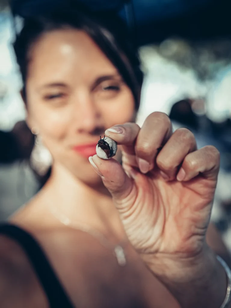 Caroline holds a snail between her fingers at an outdoor festival in Tavira, Portugal, on May 16, 2026.