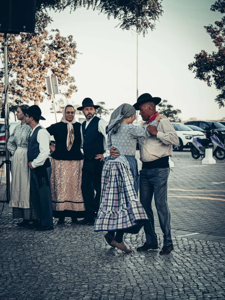 Group of people in traditional Portuguese costumes dancing in a cobbled square during an outdoor event in Tavira, Portugal.