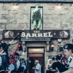 Piper parade in front of a Scottish pub in Ballater during the Highland Games