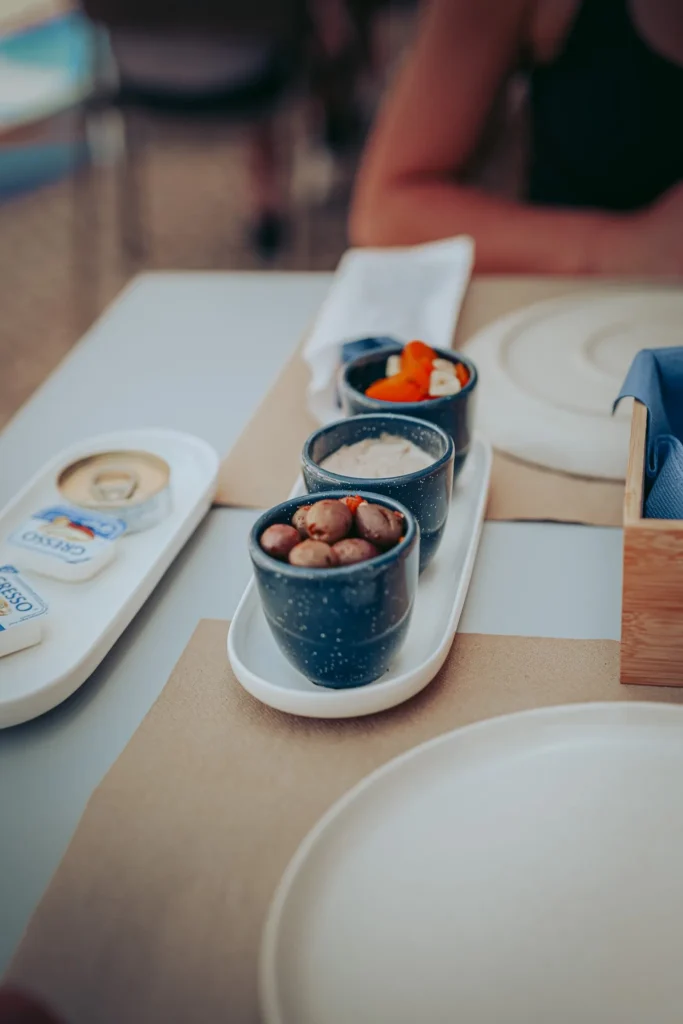 A dish composed of small bowls with olives, carrots, and artisanal sardine pâté on a beautifully set table at a restaurant in Portimão, Algarve.