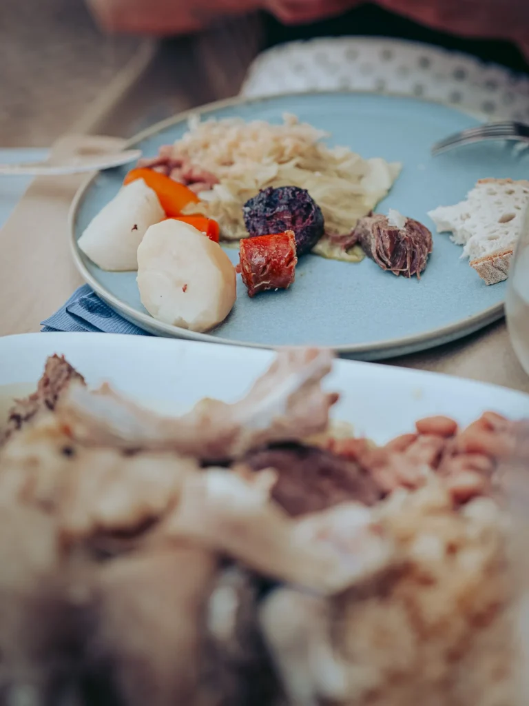 Plate of cozido à portuguesa with vegetables, cabbage, sausage, meat, and bread, served on a restaurant table in Portimão in the Algarve.