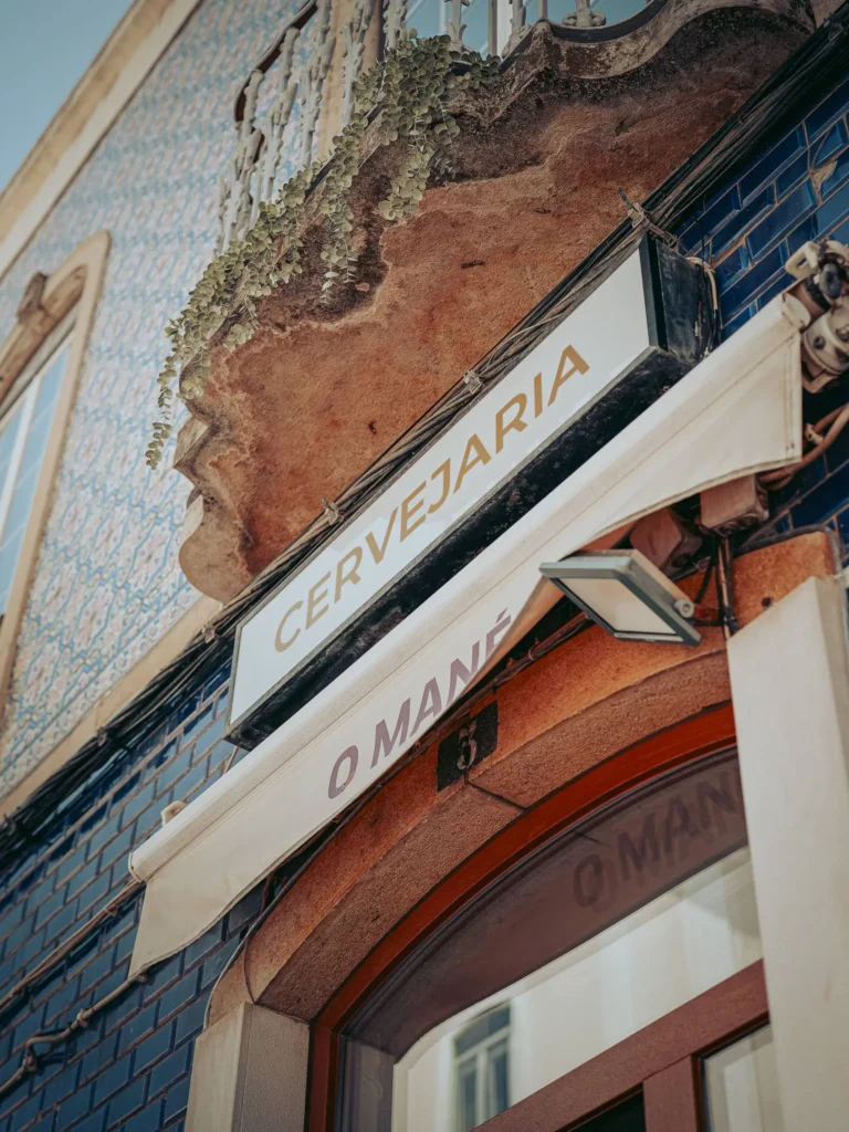 Facade of the O Mané restaurant in Portimao, with a sign indicating 'Cervejaria' and blue azulejos on the exterior walls.