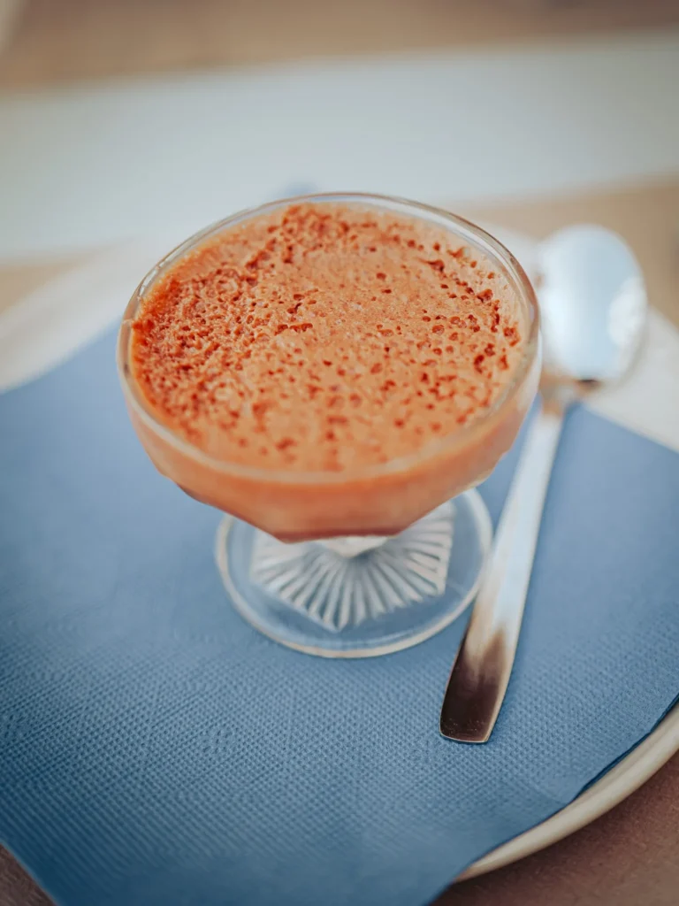 A glass of chocolate mousse is placed on a plate with a blue napkin and a spoon, in a restaurant in Portimao, Algarve.