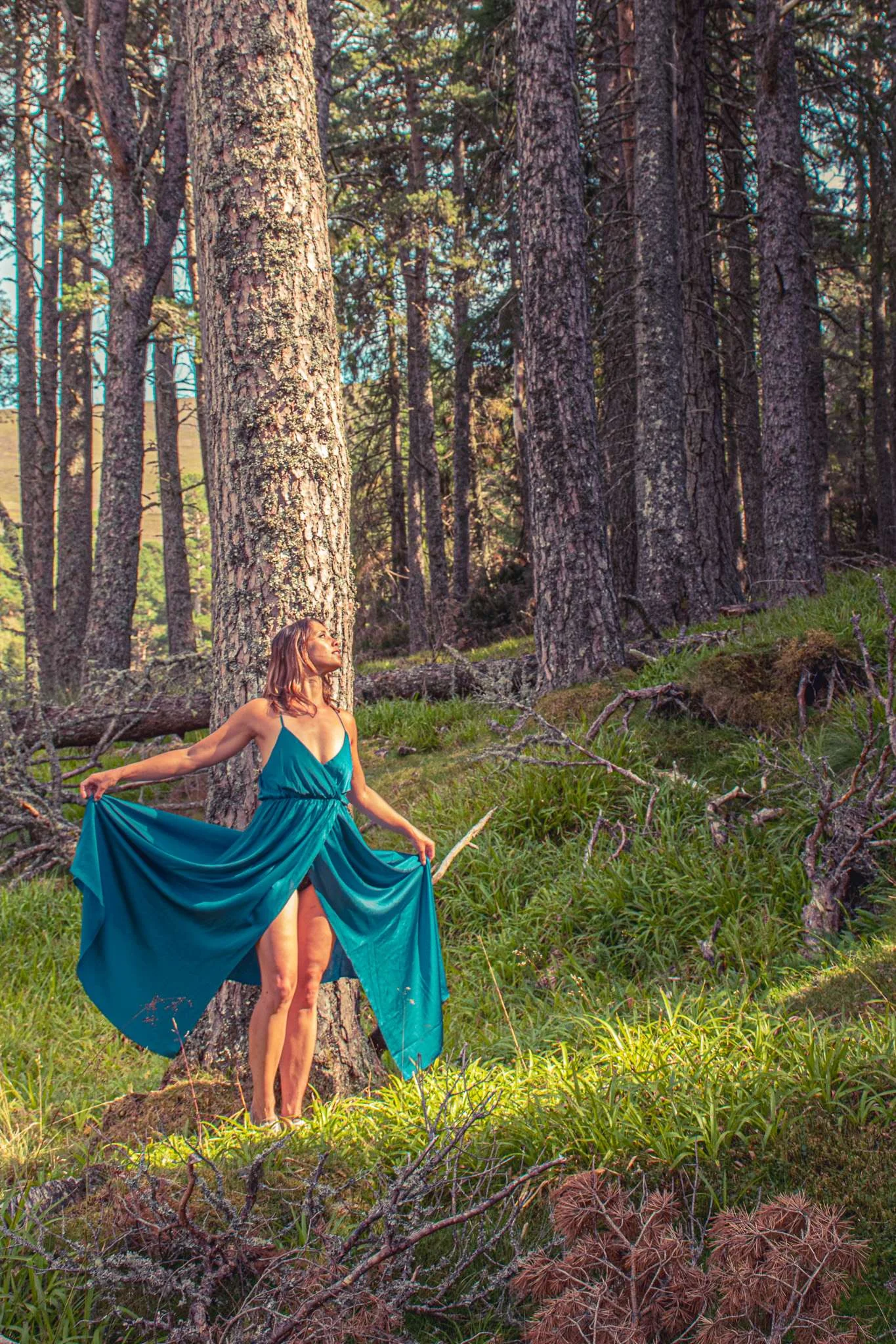 Caroline in a blue dress in a pine forest of the Cairngorms National Park