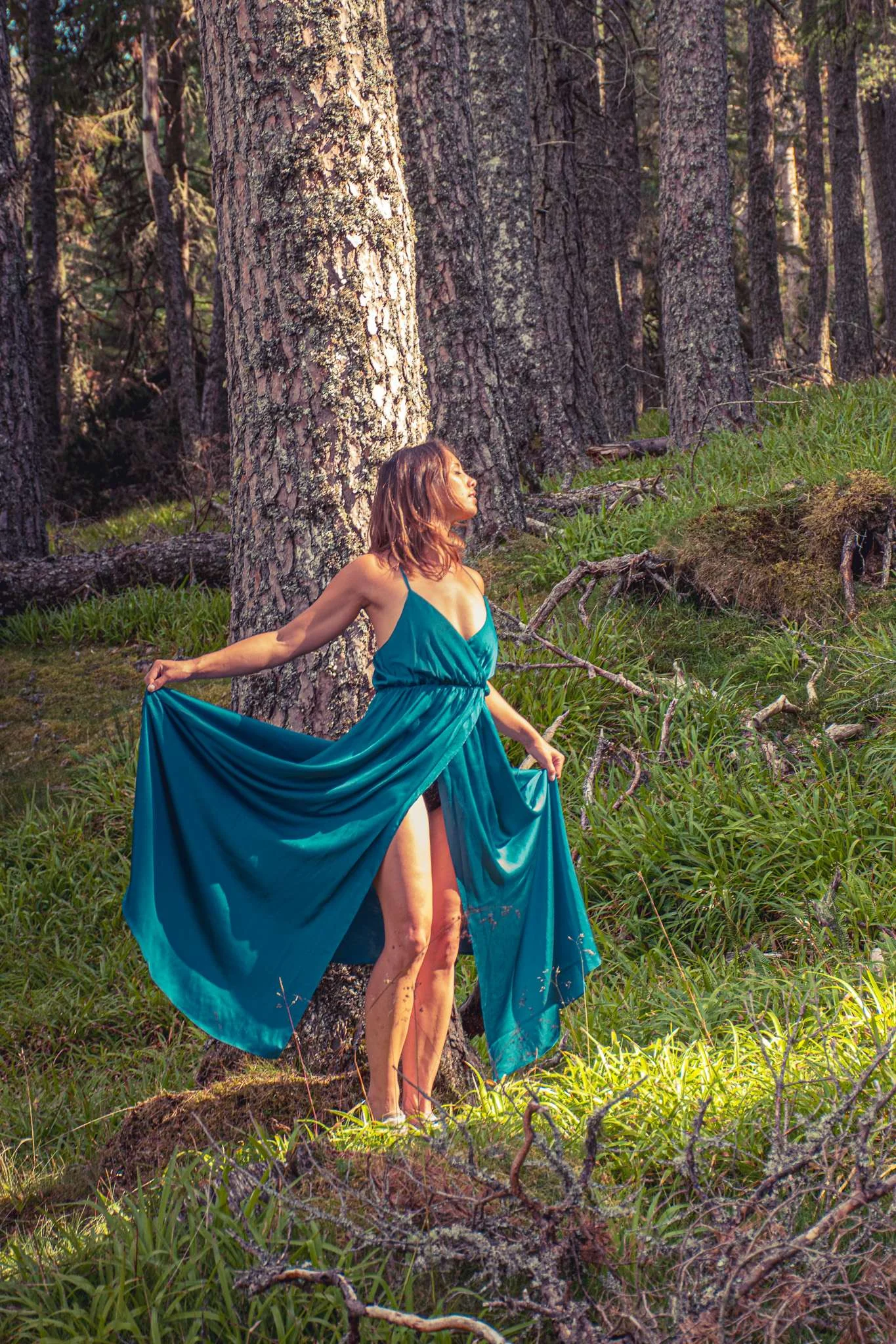 Caroline in a long blue dress poses in a dense Cairngorms forest.