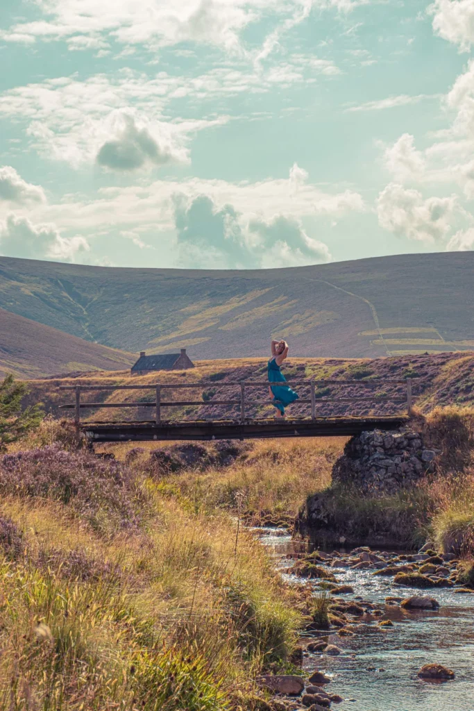 Caroline crosses a wooden bridge over a stream in the Cairngorms park