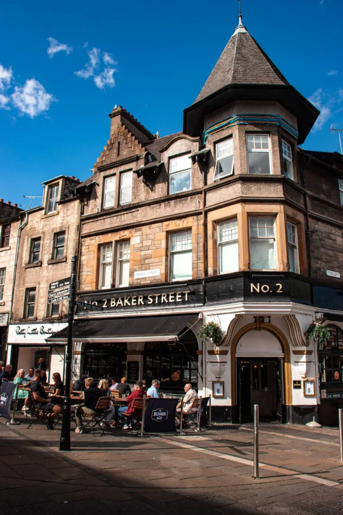 Facade of a traditional pub at the corner of a bustling street in Stirling with customers on the terrace