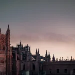 Façade et toits de la cathédrale de Séville photographiés depuis un rooftop au coucher du soleil, sans présence humaine visible.