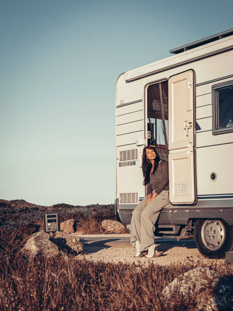 Caroline sitting at the entrance of the camper van in the great outdoors with the Aferiy Nomad 1800 station nearby