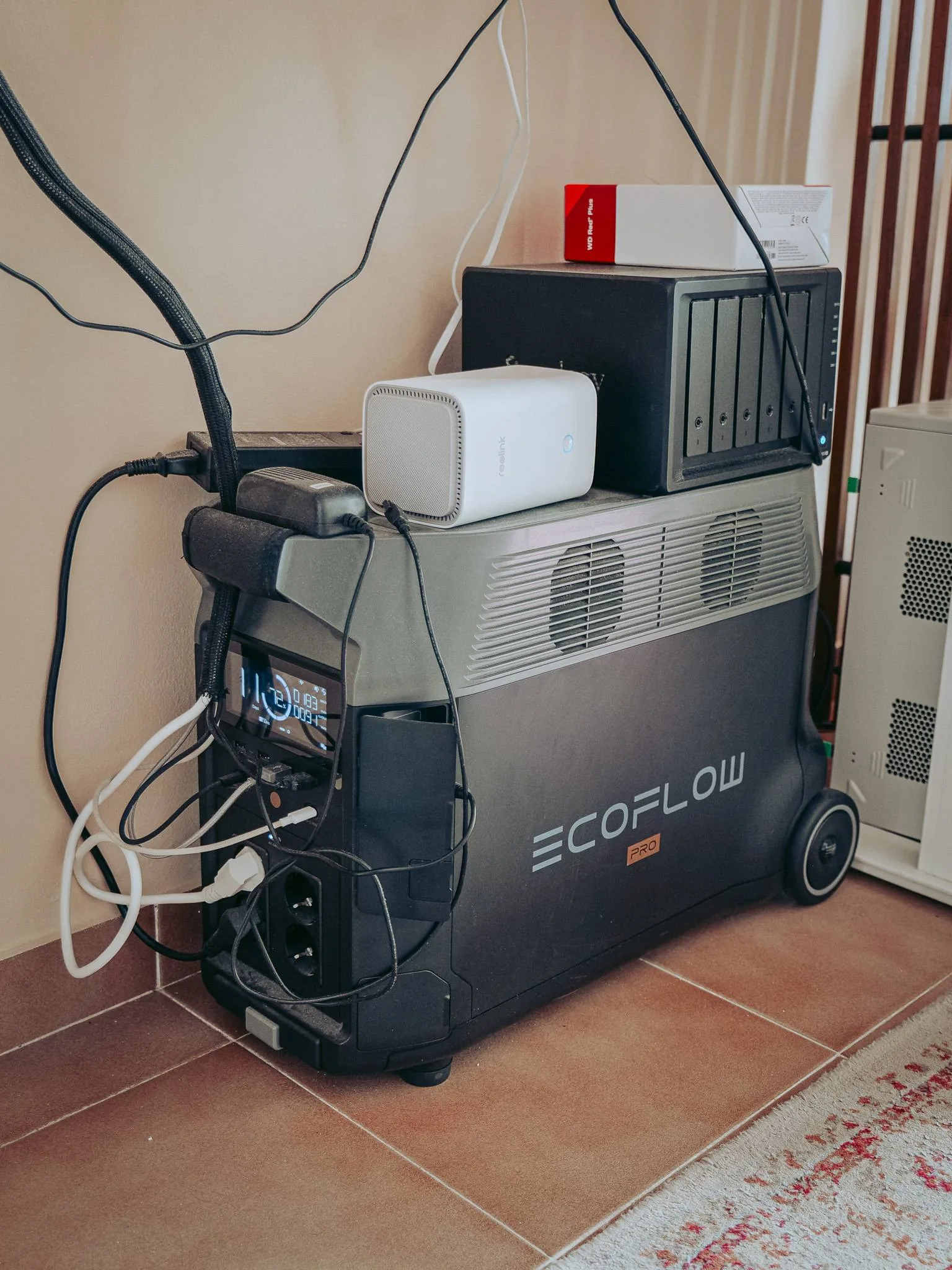 Close-up of the EcoFlow Delta Pro installed under the desk, permanently plugged in: it powers the Synology NAS and the Reolink hub placed on top. It's the workstation's inverter; when the power goes out, nothing turns off.