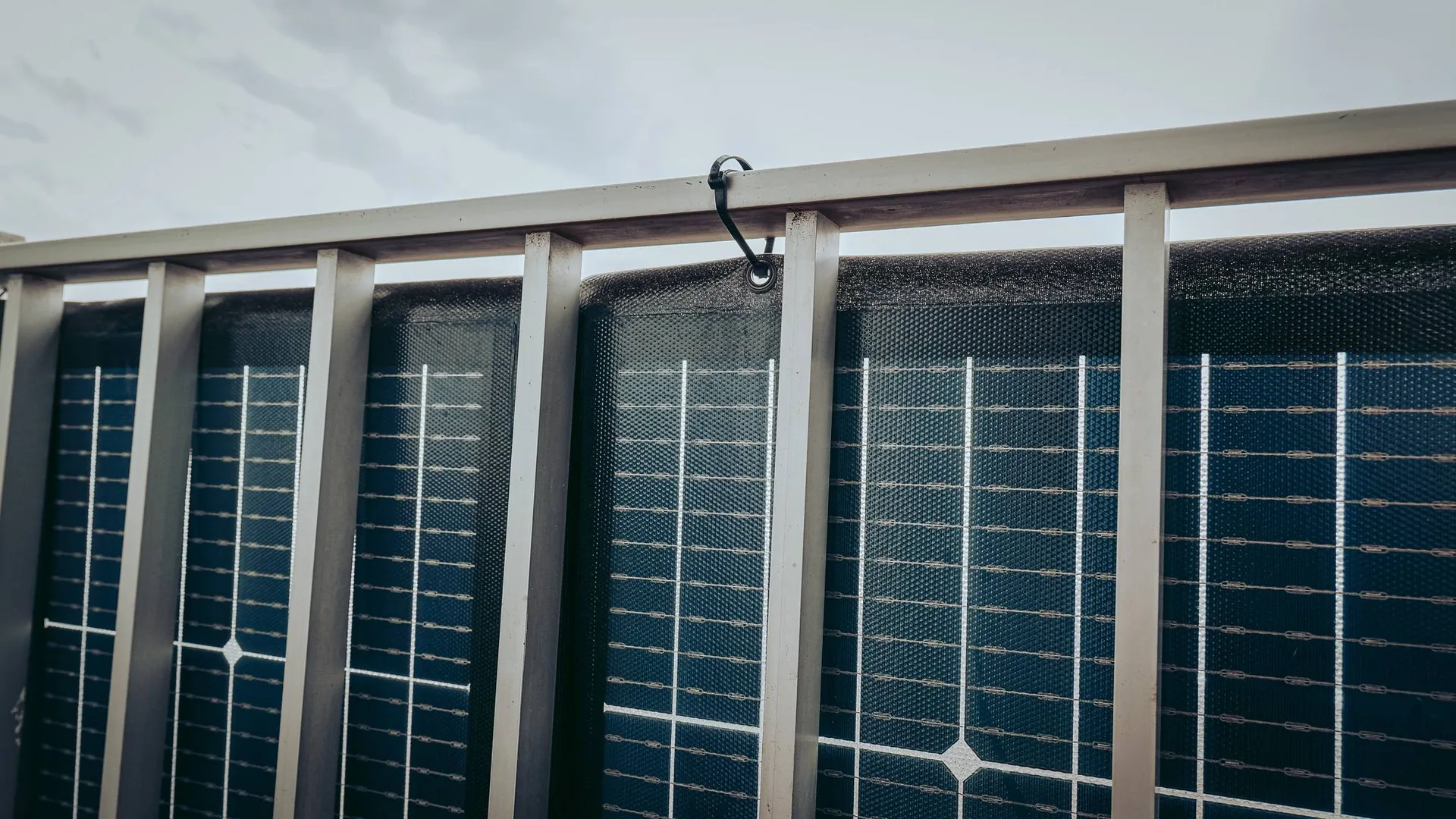 EcoFlow bifacial solar panel (200 W) attached to the metal railing of a balcony with rilsan ties, cells facing outward. A portable panel that you can take anywhere, from the van to the balcony.