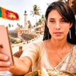 Caroline in Sri Lankan dress taking a selfie with her smartphone in front of the tea train in Sri Lanka