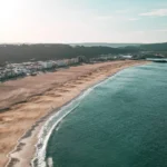 Nazaré beach in Portugal in September 2023, aerial view with the town in the background and the calm Atlantic Ocean.
