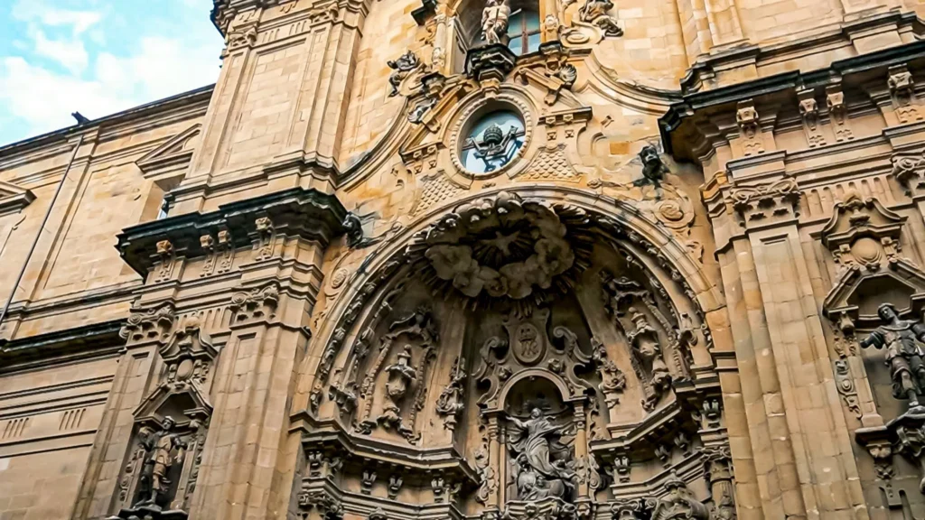 Detail of the richly carved baroque portal of the Basilica of Saint Mary of the Choir in San Sebastián: central niche topped with a radiant halo and statues of saints in gilded stone, Spanish Basque Country, November 2021.
