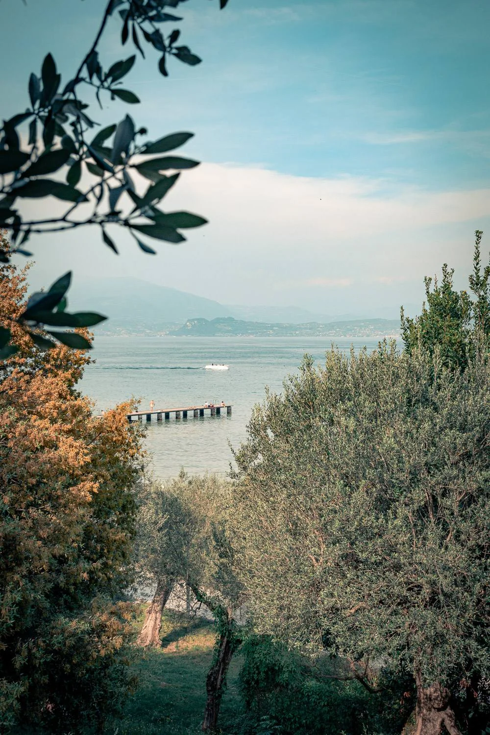 View of the lake at Sirmione with a jetty and Mediterranean trees