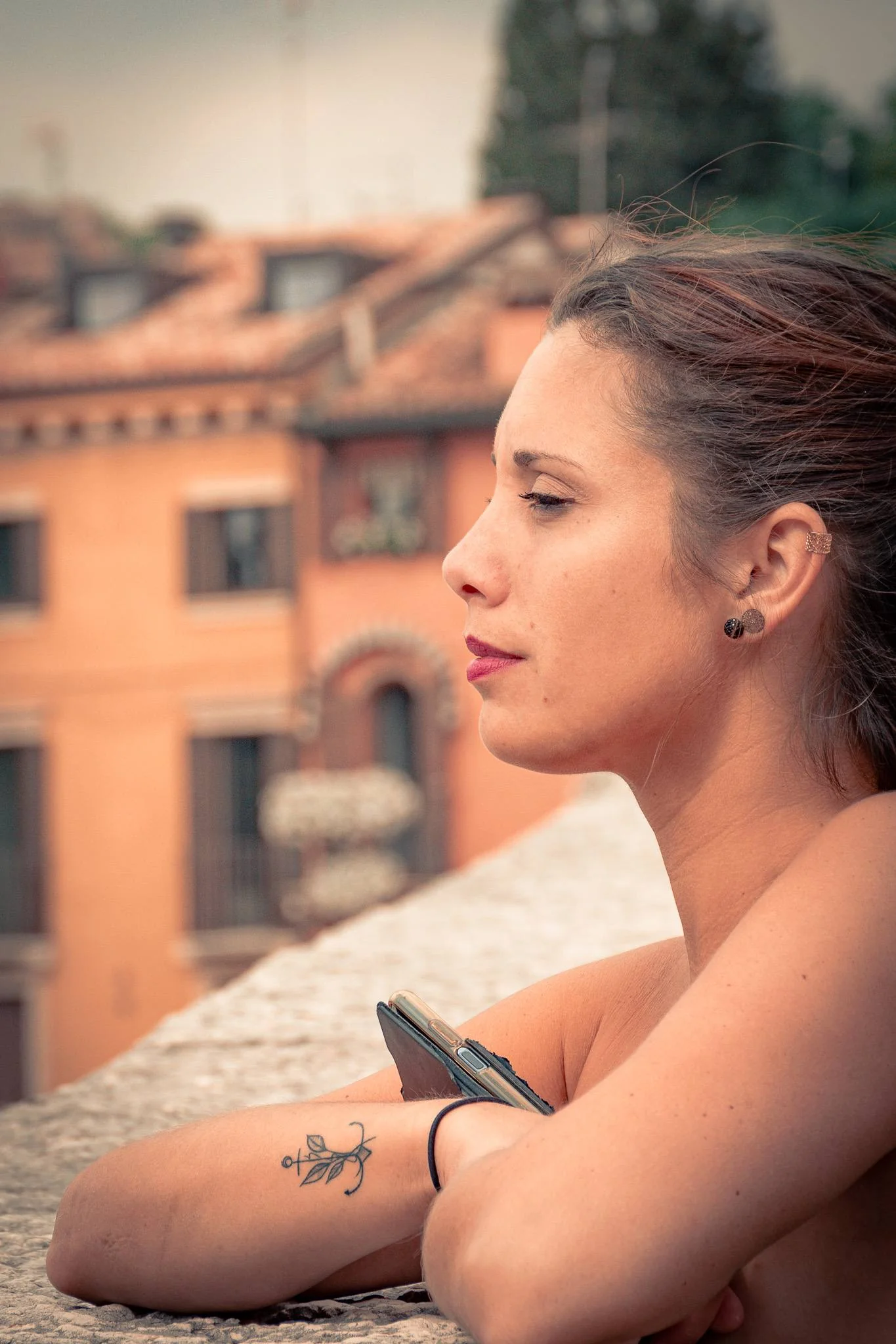 Caroline leaning against a wall in Verona with a panoramic view of the orange rooftops