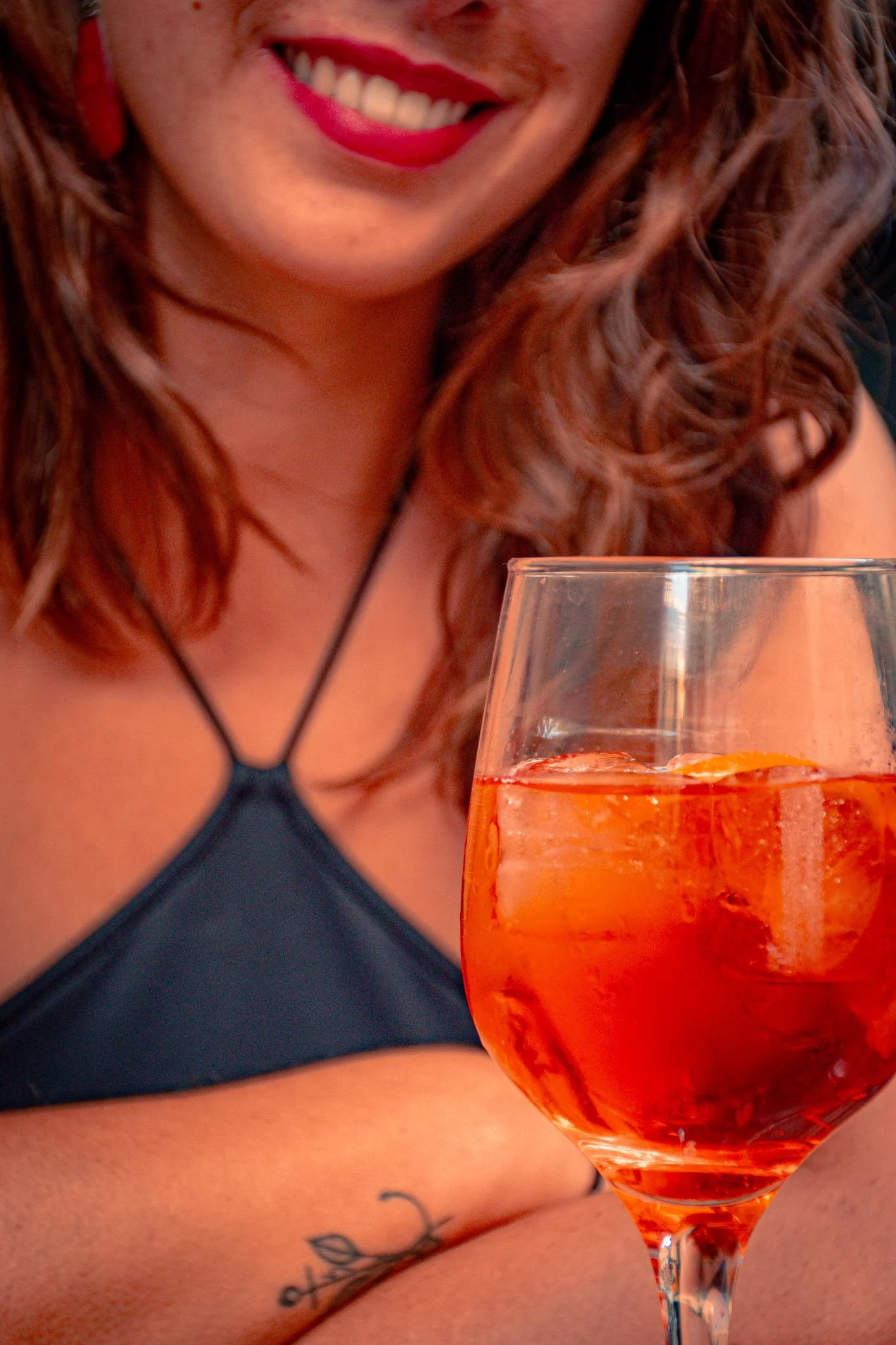 Caroline smiling in front of a glass of orange spritz on a terrace in Verona