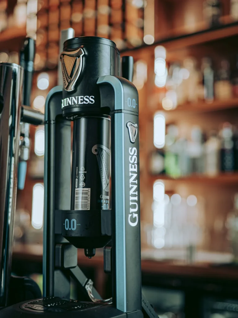 Close-up of a Guinness 0.0 beer tap installed on the bar counter of the Allan Park Hotel in Stirling, with blurred bottles in the background.