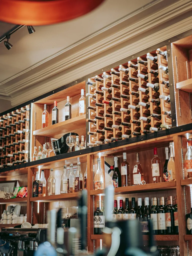 Wooden shelving in a bar with numerous bottles of wine and spirits, glasses and accessories visible, warm atmosphere typical of a hotel in Stirling, Scotland in summer.