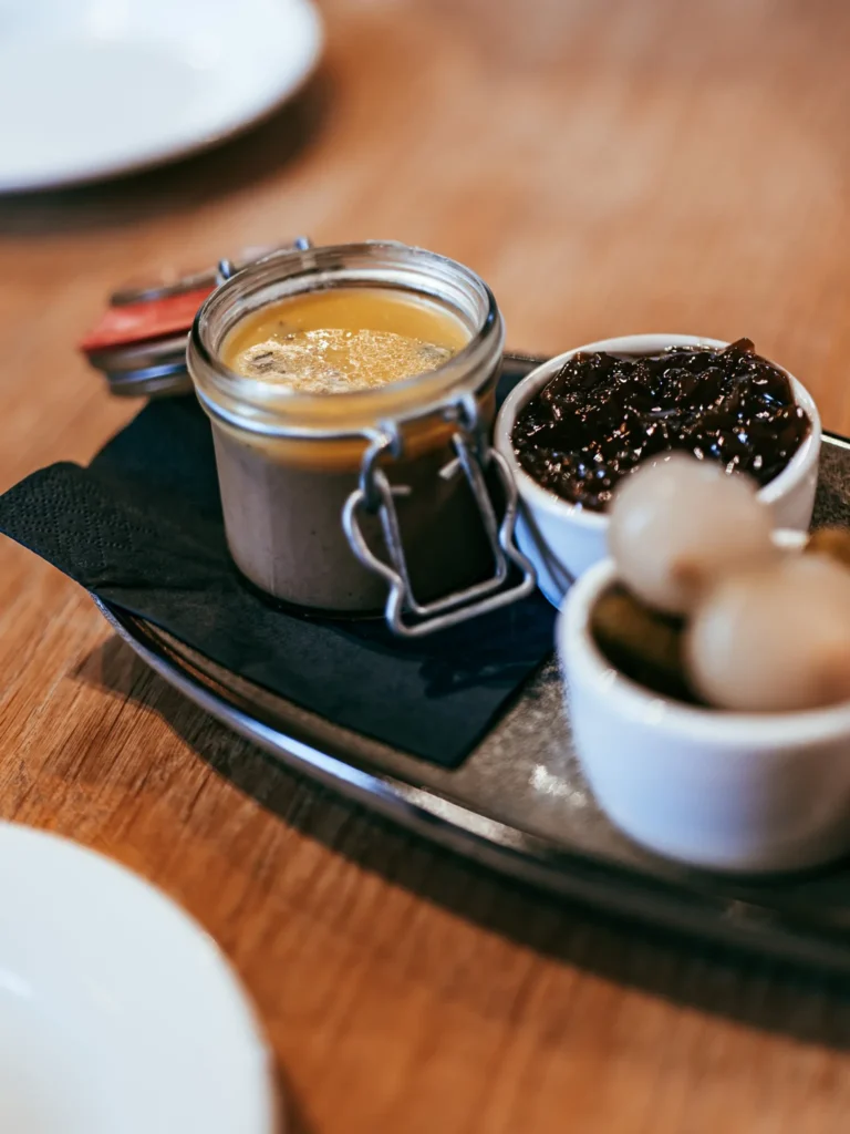 Starter served at the Allan Park Hotel restaurant in Stirling, consisting of a jar of pâté accompanied by condiments and small onions, on a wooden table in August 2026.