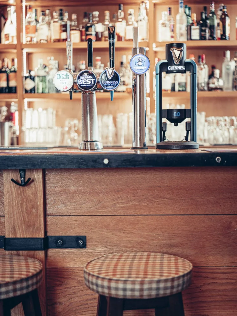 Bar counter of the Allan Park Hotel in Stirling, with beer taps and a selection of bottles in the background, Scottish atmosphere in August 2026.