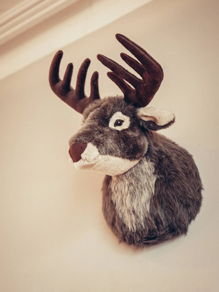 Plush wall trophy depicting a deer head mounted on a light wall, detail of the interior decoration of the Allan Park Hotel bar in Stirling in August 2026.