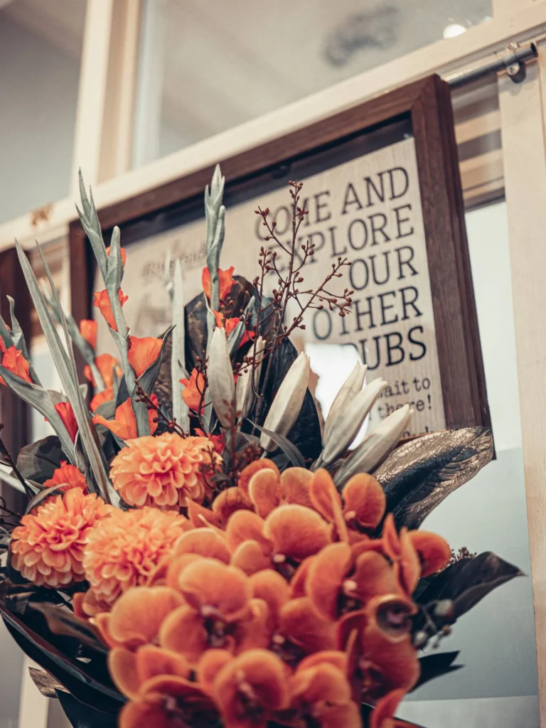 Close-up of orange floral arrangement in front of a decorative poster in the restaurant area of the Allan Park Hotel in Stirling, Scotland, in August 2026.