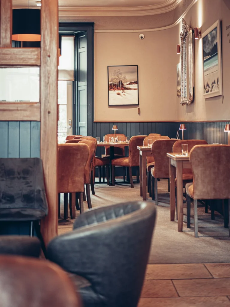 Restaurant room of the Allan Park Hotel in Stirling, Scotland, warm atmosphere with velvet armchairs and set tables, view of the wall decoration.