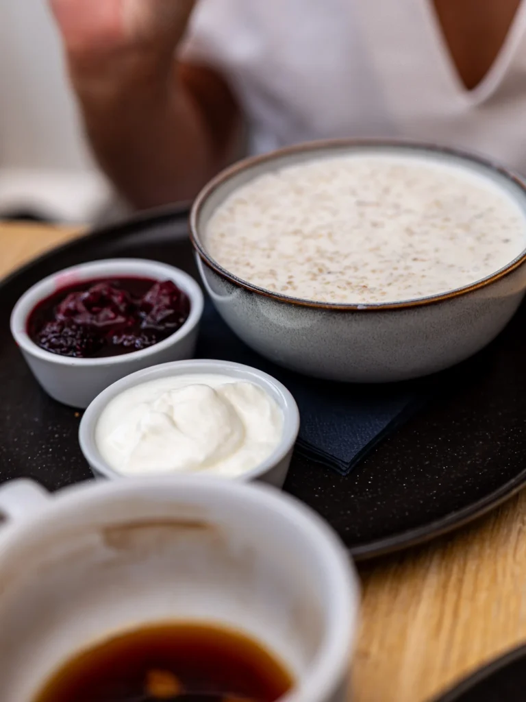 Breakfast served at the Allan Park Hotel in Stirling, with a bowl of porridge accompanied by jam, cream, and a cup of coffee on a wooden table.