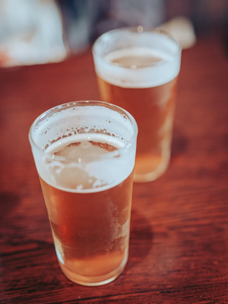 Two glasses of blonde beer placed on a wooden table in a restaurant in the Highlands of Scotland, friendly atmosphere.