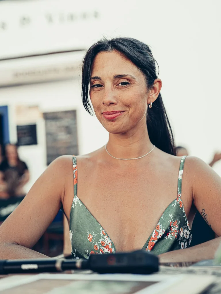 Caroline seated on the terrace at Bodeguita Salinas in Tavira, wearing a floral dress, summer and relaxed atmosphere in the Algarve.