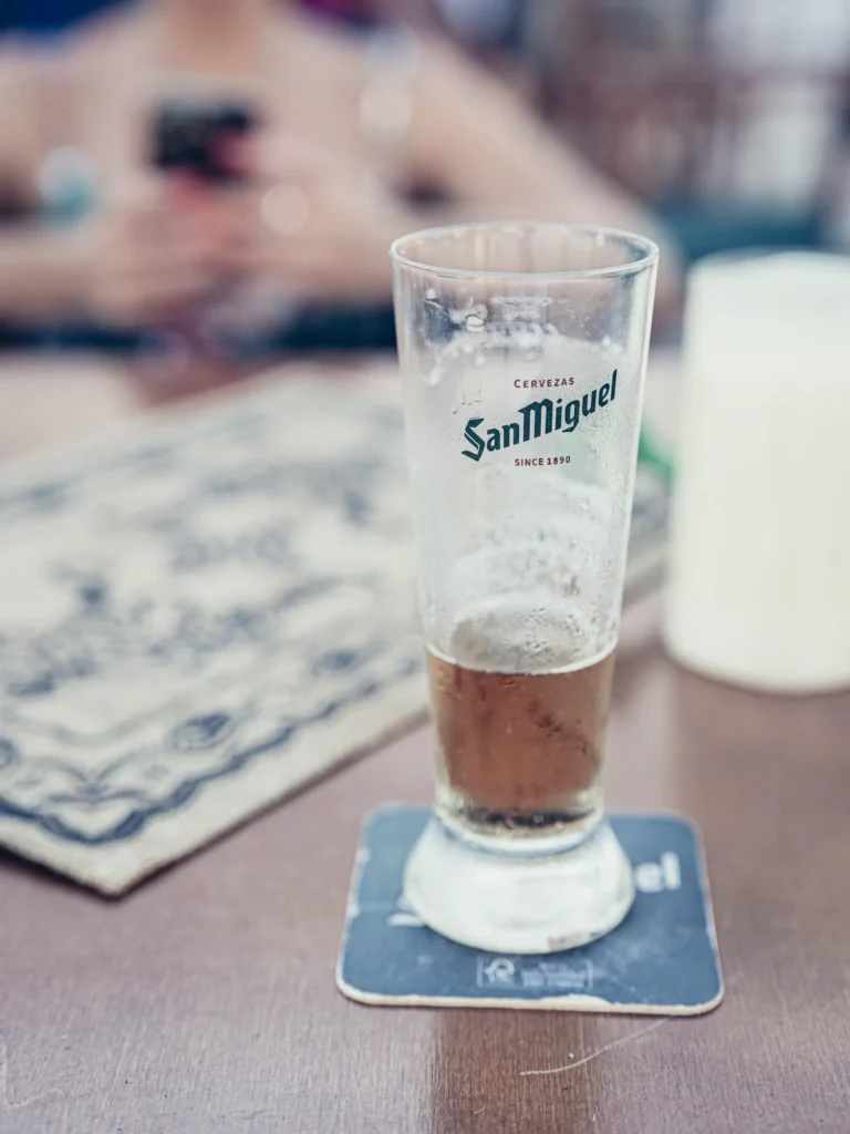 Half-empty San Miguel beer glass on a terrace table at Bodeguita Salinas in Tavira, summer vibe in the Algarve.