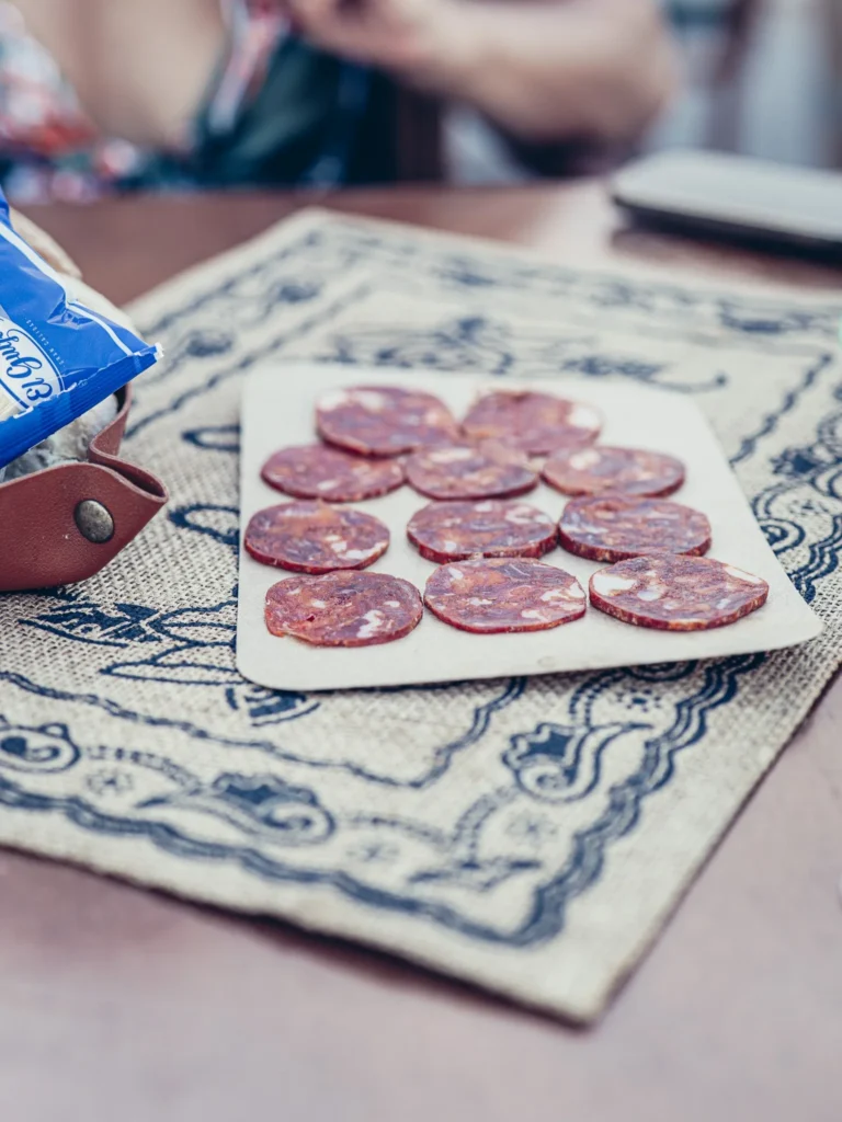 Iberian chorizo slices served as tapas at Bodeguita Salinas in Tavira, placed on a patterned tablecloth (this is not the Portuguese chouriço flambé).