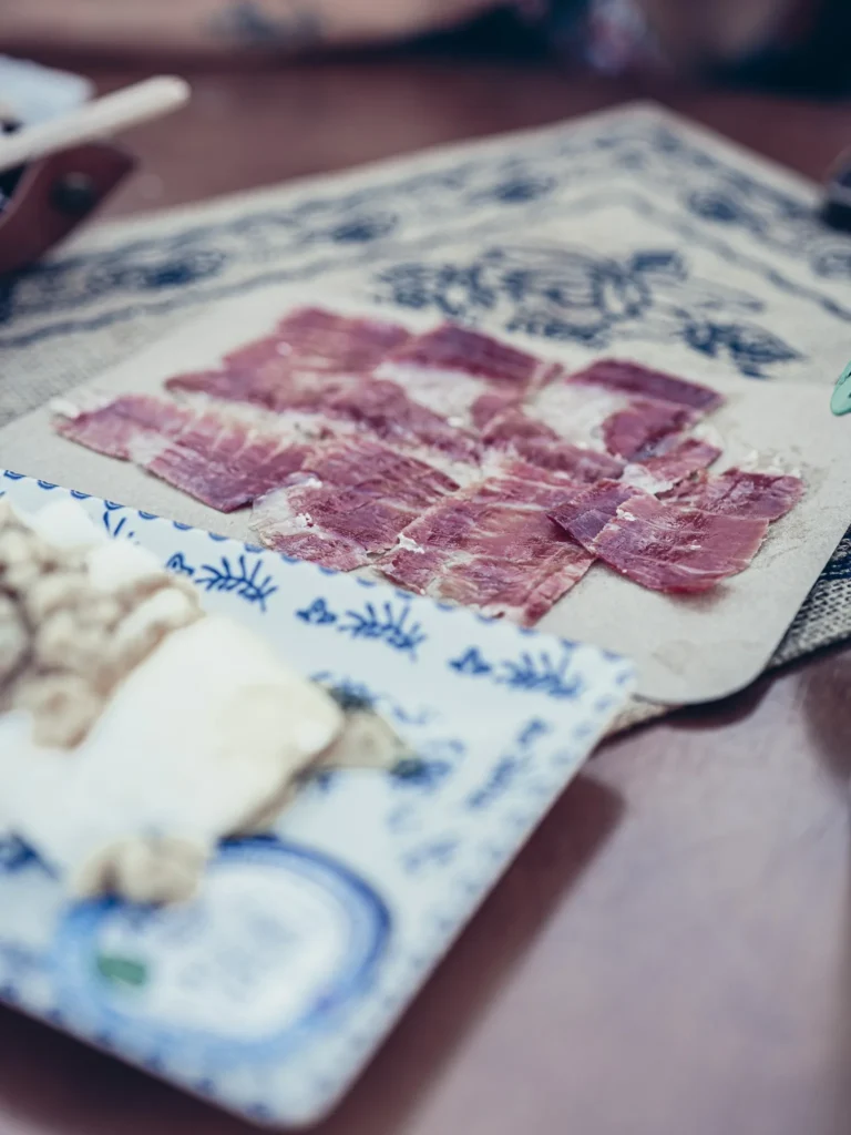 Iberian ham and fresh goat cheese plate on a table at Bodeguita Salinas in Tavira, tapas atmosphere in the Algarve.