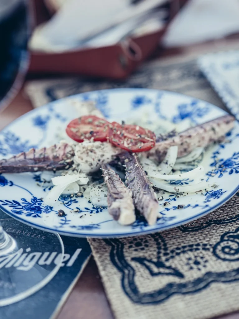 Mackerel tapas with onion and tomato, served on a blue patterned plate at Bodeguita Salinas in Tavira, Algarve.