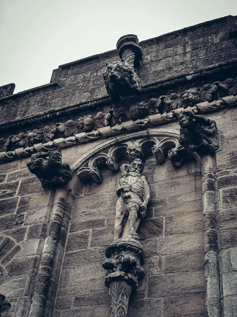 Close-up of the carved stonework on Stirling Castle, including a human figure and gargoyles.