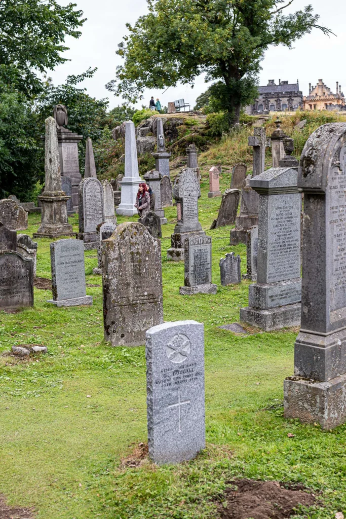 Kirkyard of the Church of the Holy Rude, in Stirling: moss and grass-covered headstones, a tree in the centre, and the bench at the back, with a panorama of the city.