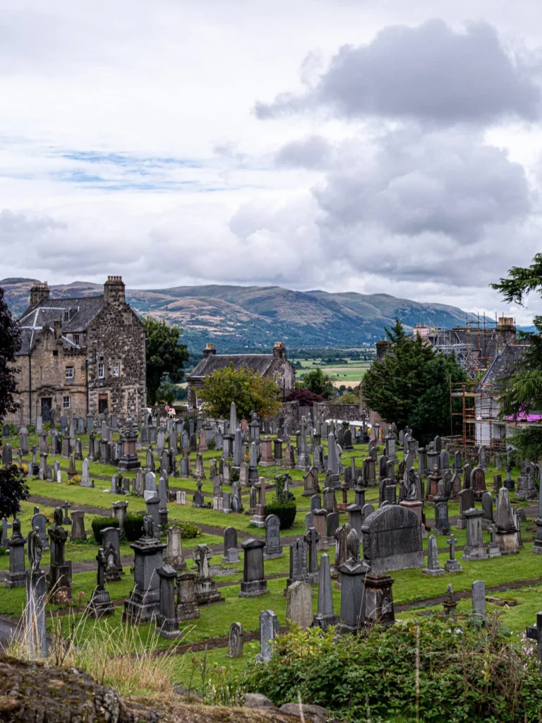 Kirkyard of the Church of the Holy Rude in Stirling: grass-covered gravestones, stone buildings, and a panorama of the countryside.