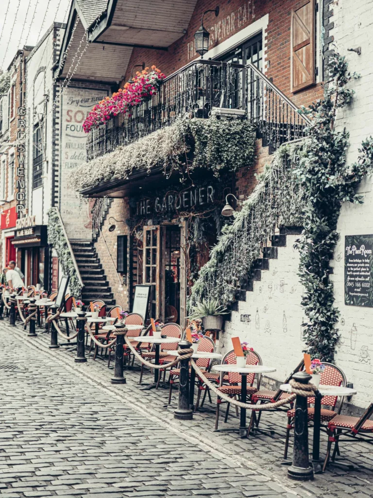 The cobbled terrace of Ashton Lane, in the West End of Glasgow: bistro chairs lined up in front of a brick facade covered in plants. A daytime view, though Xavier reckons the street comes into its own after work, and nicknames it the drinking street of the West End.