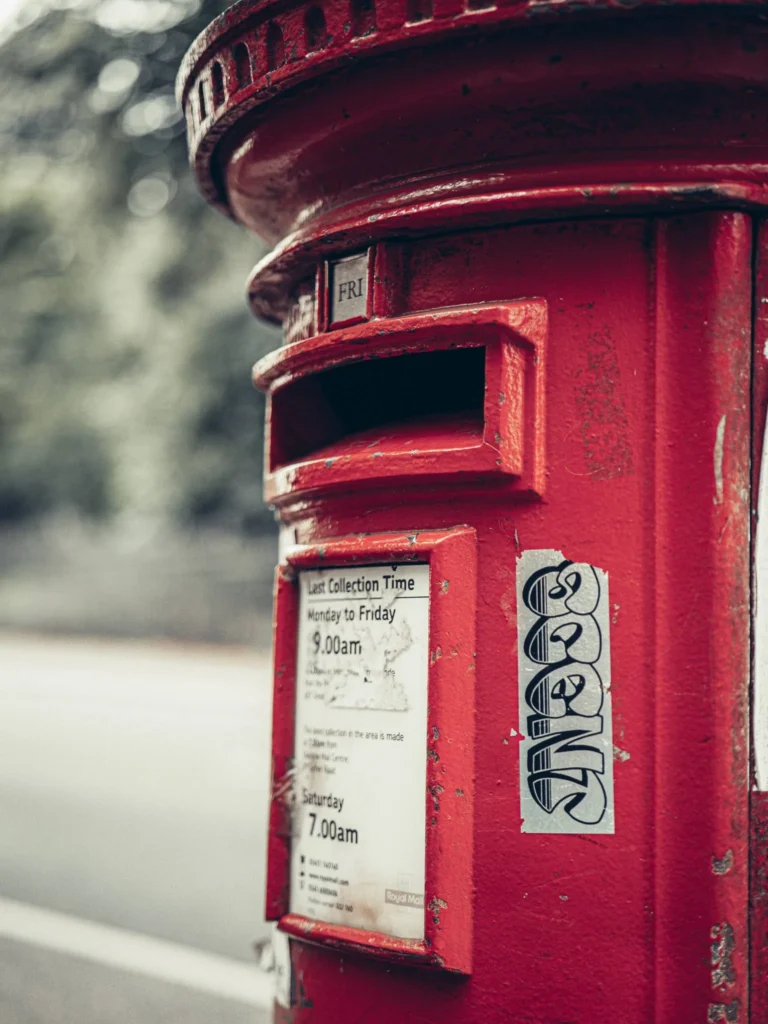 Red cast-iron pillar box on a street in Glasgow, with its collection times plate.