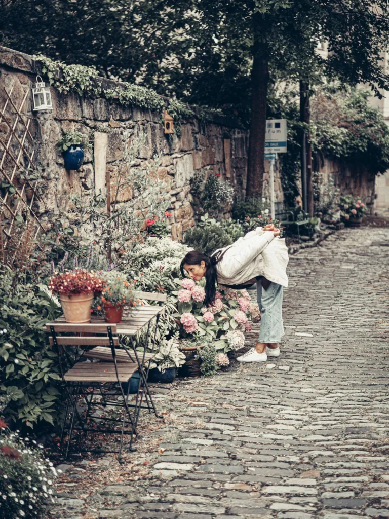 Caroline smelling hydrangeas in Park Circus Lane, Glasgow. In a setting where colour is almost absent, it is the residents' pots and flowers that stand out.