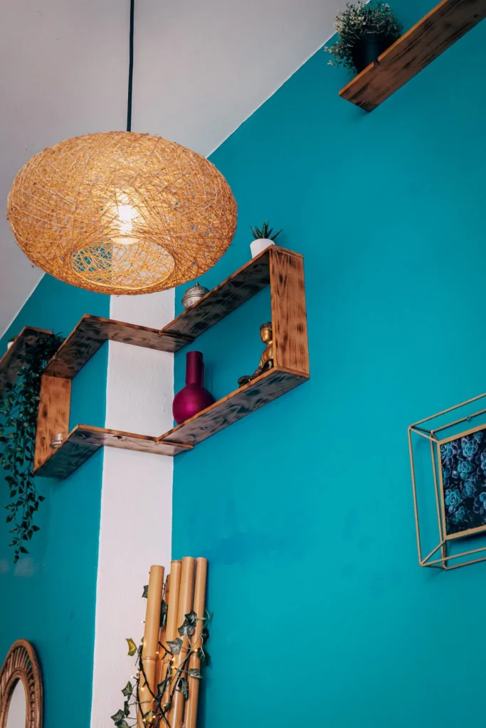 Interior decoration of the Goji restaurant in Lagos with wooden shelves, plants, a wicker pendant light, and a turquoise blue wall.