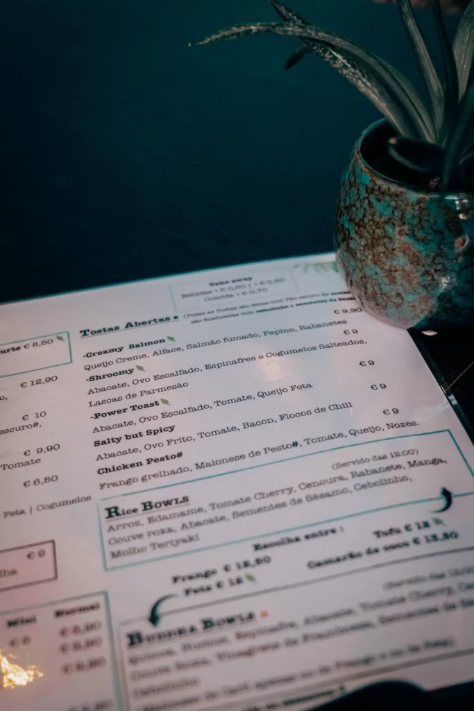 Menu of the Goji restaurant in Lagos, Algarve, placed on a dark table with a decorative potted plant beside it.